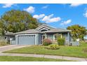 One-story home with gray exterior, two-car garage, and landscaped yard at 13229 Golf Ridge Pl, Hudson, FL 34669