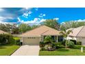 One-story home with a beige exterior, tile roof, and landscaped yard at 2681 Whispering Pine Ln, North Port, FL 34287