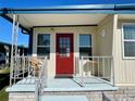 Red door entrance to the home with wicker chair and welcome sign at 34527 Violet N Dr, Pinellas Park, FL 33781