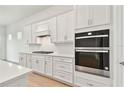 Gourmet kitchen with stainless steel appliances, white cabinets, and modern backsplash at 11208 Shoreline Trl, Parrish, FL 34219