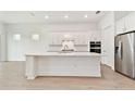 Open kitchen with white cabinets, stainless steel appliances, and large island at 11208 Shoreline Trl, Parrish, FL 34219
