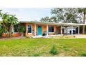 Charming single-story home featuring a vibrant exterior, covered parking, and a well-manicured lawn at 552 Trade Winds Dr, Dunedin, FL 34698