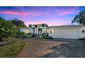 White two-story house with a three-car garage and landscaped yard at dusk at 105 Estado Ne Way, St Petersburg, FL 33704
