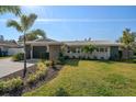 Beautiful single-story home with mature landscaping, including palm trees, a two-car garage, and a well-manicured lawn at 13632 Imperial Groves S Dr, Largo, FL 33774