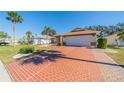 Front view of a house with a brick driveway and palm trees at 2043 Prestancia Ln, Sun City Center, FL 33573