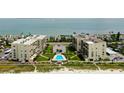 Aerial view of beachfront condos with lush green landscaping and a sparkling blue swimming pool at 1430 Gulf Blvd # 204, Clearwater Beach, FL 33767