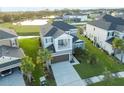 An aerial view of a two-story home showcasing its lawn, nearby community pond, and an attached two-car garage at 33975 Astoria Cir, Wesley Chapel, FL 33545
