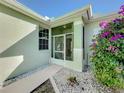 Front entrance with a screened porch, decorative metal door, and colorful landscaping at 1320 Misty Greens Dr, Sun City Center, FL 33573