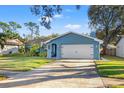 Charming light blue home with a well-manicured lawn and a two-car garage at 1422 Red Oak Dr, Tarpon Springs, FL 34689