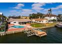 Waterfront home featuring a private pool, boat dock, and lush landscaping on a sunny day at 825 116Th Ave, Treasure Island, FL 33706