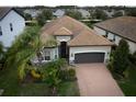 One-story house with brown roof, gray garage door and brick driveway, surrounded by neighborhood homes at 12241 Perennial Pl, Bradenton, FL 34211