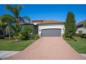One story house with gray garage door and brick driveway. Lush landscaping and palm trees complete the look at 12241 Perennial Pl, Bradenton, FL 34211