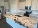 Kitchen island featuring granite countertops, a stainless steel sink, and modern fixtures at 16026 10Th E Ave, Bradenton, FL 34212