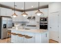 Modern kitchen with white cabinets, island, stainless steel appliances, and wood flooring at 36412 Sespe Creek Ct, Zephyrhills, FL 33540