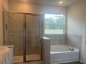 Luxurious bathroom with a glass-enclosed shower, soaking tub, and a large window with a beautiful view at 16030 10Th E Ave, Bradenton, FL 34212