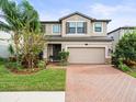 Charming two-story home with a well-maintained lawn, beautiful landscaping, and a brick driveway leading to a two-car garage at 19757 Long Lake Ranch Blvd, Lutz, FL 33558