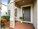 Covered front porch featuring a decorative column, brick accents, and a stylish entrance door with sidelight at 19757 Long Lake Ranch Blvd, Lutz, FL 33558