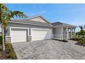 Exterior view of a house featuring a two-car garage, stone accents, and a paved driveway at 18424 Vista Park Ter, Venice, FL 34293