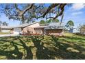 Brick house with a two-car garage and a large oak tree at 5592 Fairway Dr, Ridge Manor, FL 33523