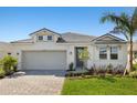 Charming single-story home featuring a gray tiled roof, a two-car garage, and manicured landscaping at 12241 Meditation Trl, Venice, FL 34293