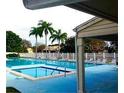 Community pool area showcasing a large pool, spa, and palm trees, enclosed by a white fence at 6262 93Rd N Ter # 3904, Pinellas Park, FL 33782