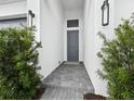 Gray front door entry with paver walkway and manicured shrubs at 9132 Bernini Pl, Sarasota, FL 34240