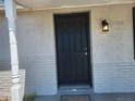 Close up of a freshly painted black front door, with a new door knob, and an updated porch light at 11608 Zimmerman Rd, Port Richey, FL 34668