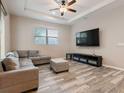 Spacious living room with L-shaped sofa, wood-look floors, and a large TV at 6904 E 18Th Ave, Tampa, FL 33619