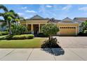 Lovely yellow home featuring tropical landscaping, brick driveway, and inviting curb appeal at 721 Manns Harbor Dr, Apollo Beach, FL 33572