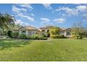 Single-story home with a large lawn, mature trees, and solar panels at 3416 57Th E St, Bradenton, FL 34208