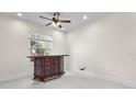 Cozy bonus room featuring tile floors, neutral walls, a ceiling fan, and a wooden bar at 611 June Lake Ln, Brandon, FL 33510