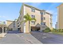 Inviting exterior view of a tan multi-story condo building featuring convenient covered parking and lush landscaping at 399 150Th Ave # A203, Madeira Beach, FL 33708