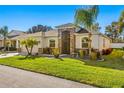 Tan house with palm trees and a neatly landscaped lawn at 10431 Machrihanish Cir, San Antonio, FL 33576