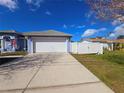 Attached garage with a white door on a blue single-story house with a concrete driveway and a white fence at 10232 Oakhurst Rd, Largo, FL 33774