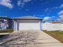 Front view of a blue home's two-car garage with a white door and an extended driveway on a sunny day at 10232 Oakhurst Rd, Largo, FL 33774