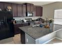 Modern kitchen with dark wood cabinets, granite countertops, and stainless steel appliances at 14207 Alistar Manor Dr, Wimauma, FL 33598