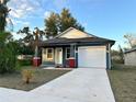 Newly built house featuring gray siding, a white garage door, and red brick pillars at 3208 Deleuil Ave, Tampa, FL 33610