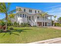 Beautiful home featuring pristine white exterior, lush green lawn, mature palm trees, and manicured landscaping at 6189 Leeland S St, St Petersburg, FL 33715