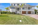 Charming white home featuring lush front yard landscaping and a brick driveway leading to the attached garages at 6189 Leeland S St, St Petersburg, FL 33715