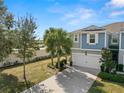 Two-story townhome with blue siding, two-car garage, and palm trees at 2101 Sunset Wind Loop, Oldsmar, FL 34677