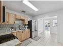 Bright kitchen featuring stainless steel appliances, light wood cabinets, granite countertops, and stylish backsplash at 3918 W Fig St, Tampa, FL 33609