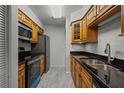 Galley kitchen featuring granite countertops, stainless steel appliances, and warm wooden cabinets at 13608 S Village Dr # 6105, Tampa, FL 33618