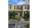 Two-story yellow townhome with gray door, landscaping, and walkway at 1252 Costa Mesa Dr, Wesley Chapel, FL 33543