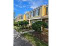 Row of townhomes with yellow and beige exteriors and landscaping at 1252 Costa Mesa Dr, Wesley Chapel, FL 33543