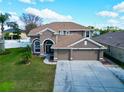 Two-story house with tan exterior, three-car garage, and manicured lawn at 2012 Fern Ridge Ct, Holiday, FL 34691