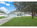 Light teal house with a white fence, landscaping, and a large tree in the front yard at 5112 Teather St, Spring Hill, FL 34608