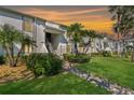 Condo exterior showcases lush landscaping, tropical palms, and beautiful sunset skies at 122 E Cypress Ct # 22, Oldsmar, FL 34677