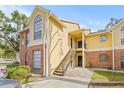 Two-story condo building with brick and yellow siding, stairs, and parking at 8722 Mallard Reserve Dr # 204, Tampa, FL 33614