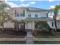 Two-story light green house with a white door, landscaping, and a metal roof on a sunny day at 322 Ibisview Ln, Apollo Beach, FL 33572