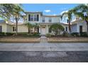 Two-story light green house with a white door, landscaping, and a metal roof on a sunny day at 322 Ibisview Ln, Apollo Beach, FL 33572